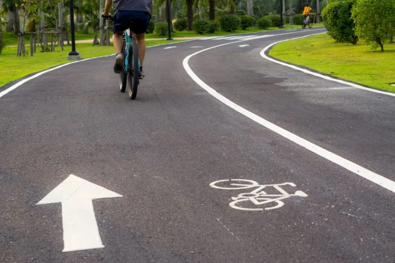 Smooth asphalt bike path with white edge lines, a direction arrow and a bicycle symbol, an example of bike path paving in Spokane, WA