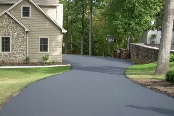 Smooth black asphalt driveway curving past a stone and siding home, illustrating an asphalt driveway in Spokane, WA